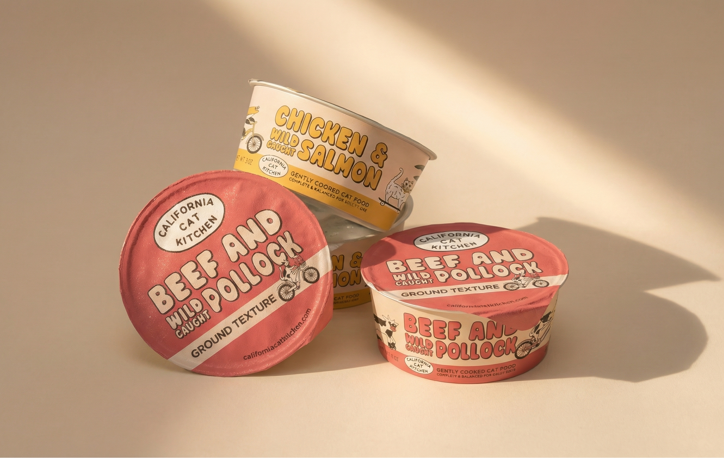 Four round yogurt-style containers of cat food on a beige background with  studio lighting